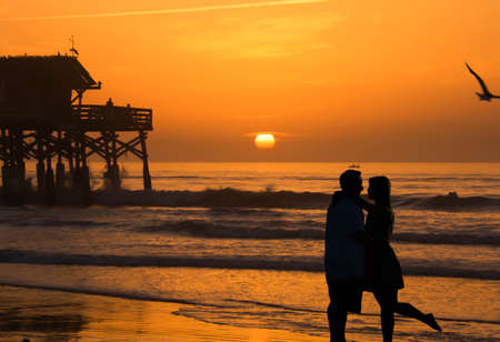 Silhouette of lovers kissing on the beach and sunrise.の素材