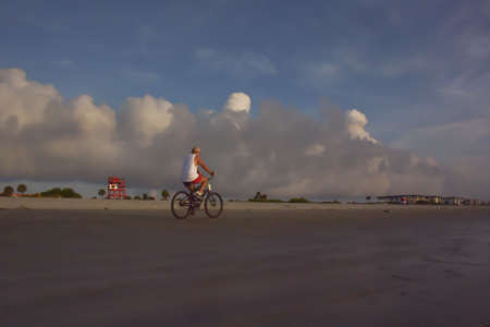 man riding bike at the beach with clouds,の写真素材