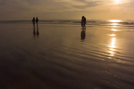 Happy family walking on the beach at sunrise for holiday timeの写真素材