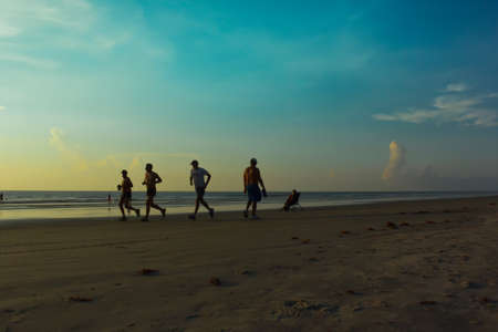 Happy family walking on the beach at sunrise for holiday timeの写真素材
