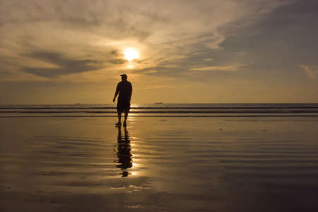 Happy family walking on the beach at sunrise for holiday timeの写真素材