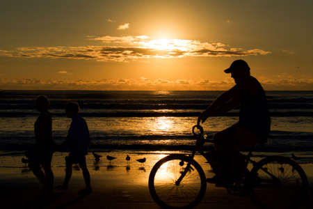 people walking and riding bike at the beachの写真素材