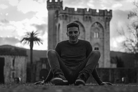 Model sit down in the floor with a castle behind himの写真素材