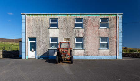 A typical abandoned Irish house with an old tractor on the doorstep in County Donegal.のeditorial素材