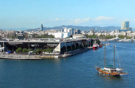 Port Vell, Barcelona. A schooner arrives at the port of Barcelona with the silhouette of the city in the backgroundのeditorial素材