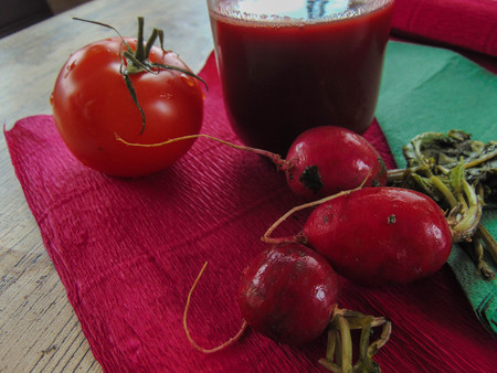 Radish juice with tomato on a pink background next to a green napkin.の写真素材