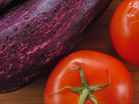 Eggplants with tomatoes on a rustic wooden board.の写真素材