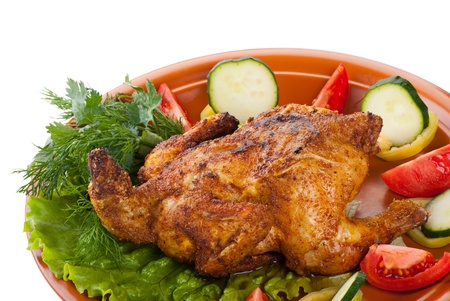 fresh grilled whole chicken with cucumber, raw tomatoes on plate with leaf lettuce isolated over white backgroundの写真素材
