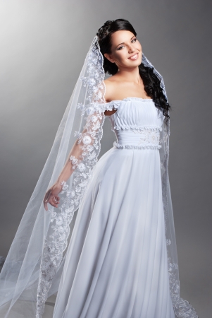 beautiful bride is standing in wedding dress on grey backgroundの写真素材