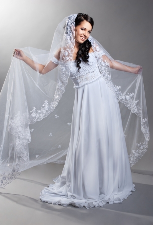 beautiful bride is standing in wedding dress on grey backgroundの写真素材