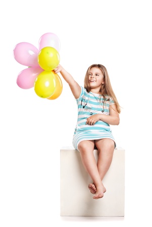 Little girl playing with colourful balloons on a white backgroundの写真素材