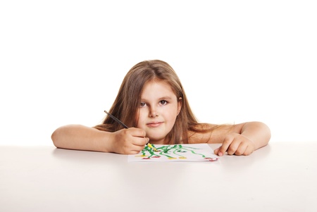 small beautiful girl with brush paints flowers on paper over white backgroundの写真素材