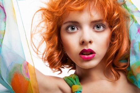 Girl with beautiful red hair and colorful dress and fabric over white backgroundの写真素材
