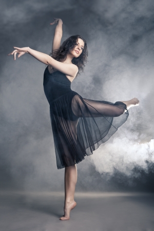 Modern style dancer posing on a studio grey background in fogの写真素材