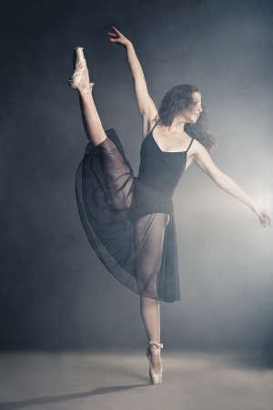 Modern style dancer posing on a studio grey background in fogの写真素材