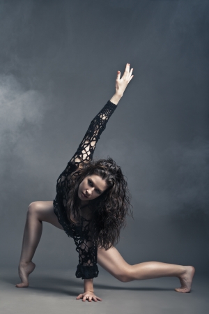 Modern style dancer posing on a studio grey background in fogの写真素材