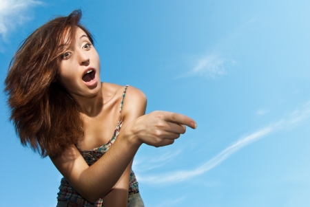 Portrait of a beautiful young woman amazed and pointing against the sky - Outdoorの写真素材
