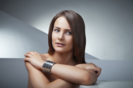 Beautiful woman with long brown straight hairs on grey backgroundの写真素材