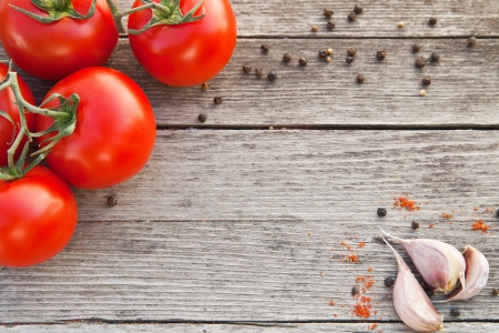 Dewy red tomatoes with pepper and garlic on old wooden tableの写真素材