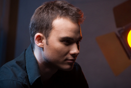 Closeup portrait of a sexy male model in studio on dark grey background with flashesの写真素材