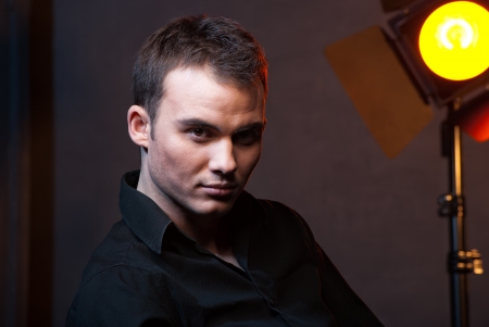 Closeup portrait of a sexy male model in studio on dark grey background with flashesの写真素材