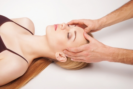 Young bright woman receiving a head massage in a spa centreの写真素材