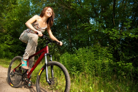 Portrait of pretty young woman with bicycle in a park smiling - Outdoorの写真素材