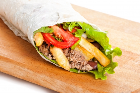 beef burrito with yellow and red peppers, fried potato and tomato on plateの写真素材