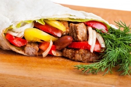 beef burrito with yellow and red peppers, onion and tomato on plateの写真素材