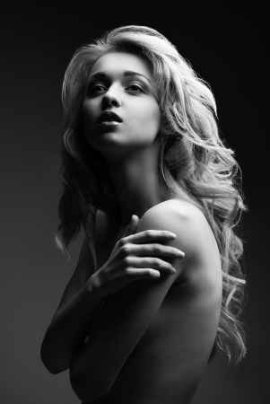 Portrait of beautyful naked posing blond woman with long curly hair on black background. Black and whiteの写真素材