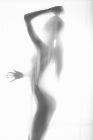 The body of a beautiful naked woman through the transparent fabric on a light backgroundの写真素材