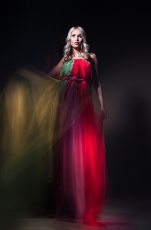 Young beautiful female model in colorful dress on black backgroundの写真素材