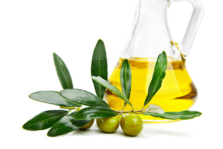 Glass bottle of virgin olive oil and branch with olives isolated on whiteの写真素材