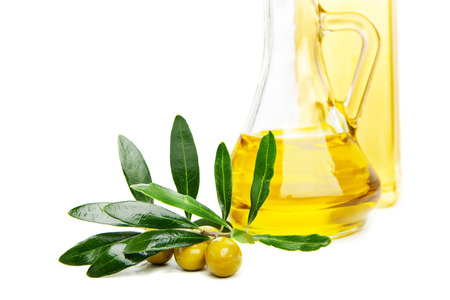 Glass bottle of virgin olive oil and branch with olives isolated on whiteの写真素材