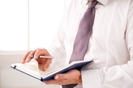 Businessman standing in office holding diary on whiteの写真素材