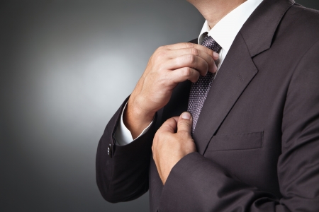 portrait of the beautiful businessman in black costume tie one's necktieの写真素材