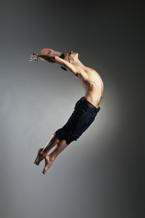 Caucasian man gymnastic leap posture on grey backgroundの写真素材