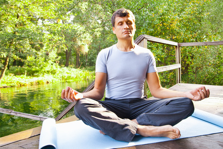 young man doing yoga (lotus pose) in the parkの写真素材