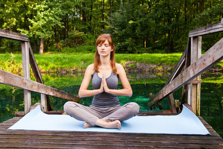 Young girl doing yoga (lotus pose) in the parkの写真素材