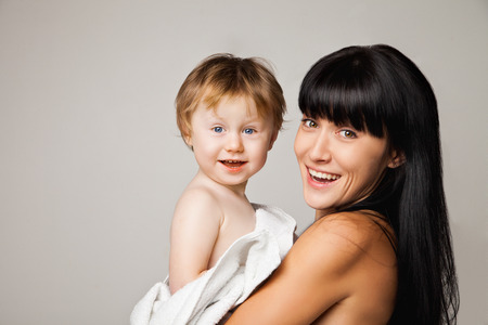 Young mother with her baby after bathing in a white towelの写真素材