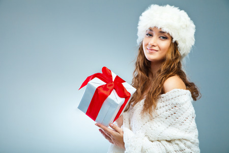 Young attractive girl in Christmas style holding present over greyの写真素材