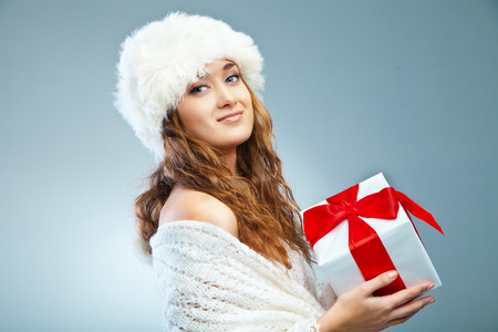 Young attractive girl in Christmas style holding present over greyの写真素材