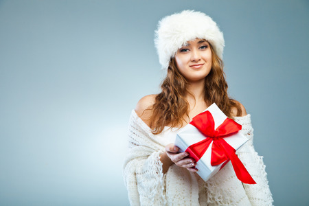 Young attractive girl in Christmas style holding present over greyの写真素材