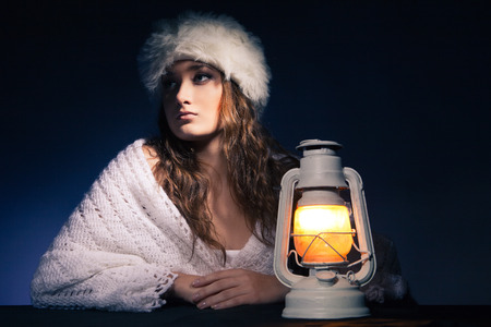 portrait of beautiful woman sitting with lantern over dark backgroundの写真素材