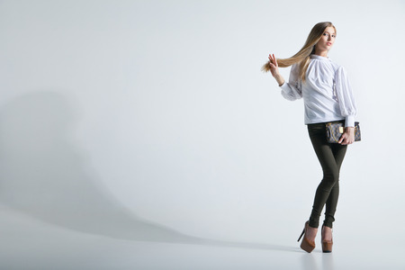 Full length casual young fashionable woman with a bag in light backgroundの写真素材