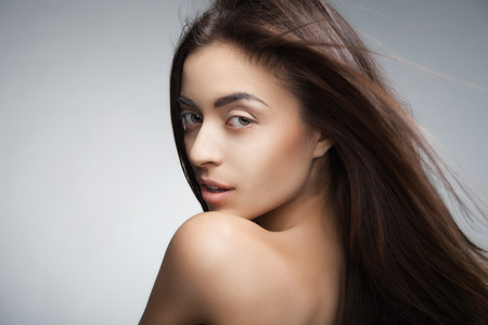 Portrait of attractive caucasian smiling woman with long hair on grey background.Looking at cameraの写真素材