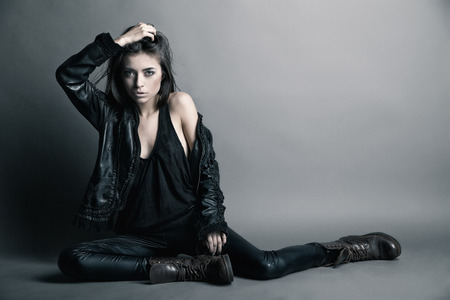 Fashion model wearing leather pants and jacket posing on grey backgroundの写真素材