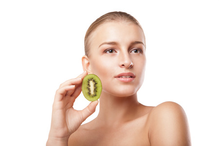 Beautiful smiling woman holding piece of kiwi. Beauty shotの写真素材