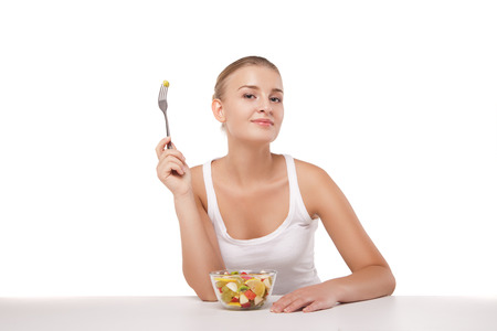 Pretty girl eating fruit salad, healthy fresh breakfast, dieting and health care concept isolatedの写真素材