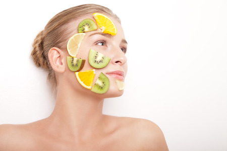 Beautiful young smiling cheerful woman with fruit mask on her face isolated on white backgroundの写真素材
